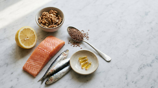 Salmon, sardines, walnuts, flaxseed and softgels on marble — omega-3 deficiency and food sources