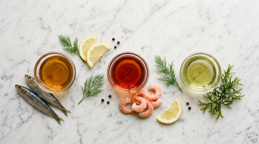 Fish oil, krill oil, and algae oil softgels in three ceramic dishes on marble — comparison