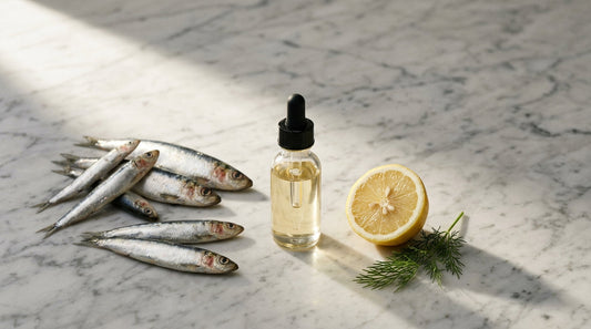 Small wild fish, a lab vial of fish oil, and lemon on marble — mercury and heavy metals in fish oil